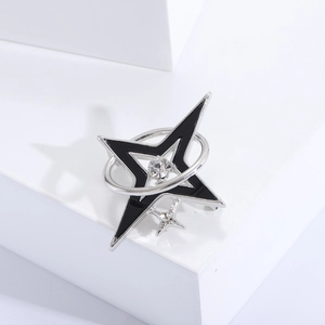 Silver star brooch with black enamel and orbital ring shown on a white pedestal
