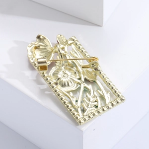 Detail of the golden rectangular hollow flower brooch back with a secure metal pin clasp
