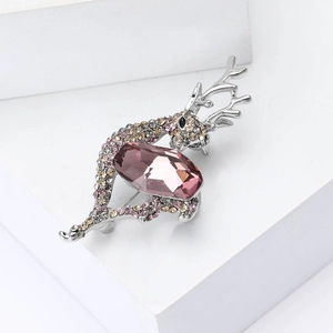 Macro shot of silver deer brooch featuring a faceted purple gemstone and sparkling rhinestones