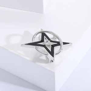 Macro detail of silver star brooch with black enamel inlay and sparkling center crystal