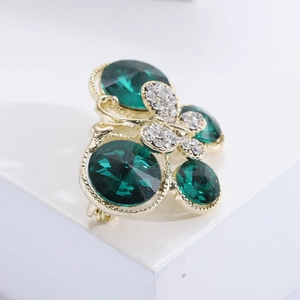 Détail macro de broche papillon avec pierres précieuses vert foncé et cristaux blancs
