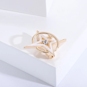 Detailed shot of a gold star brooch with white enamel inlay and central sparkling zircon