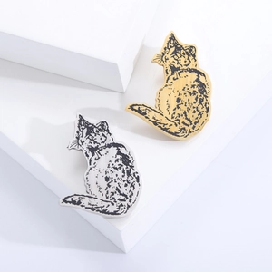 Cute gold and silver cat-shaped stainless steel brooches on a white display stand