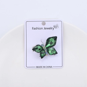 Detailed macro of a green crystal butterfly brooch with colorful rhinestones on a card