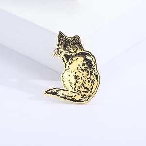 Detailed close-up of a golden cat brooch with intricate black etched texture details