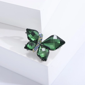 Macro shot of green crystal butterfly brooch with silver alloy base on white background
