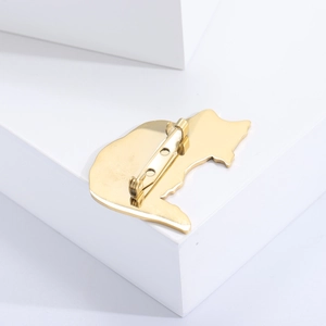 Macro shot of the gold cat brooch reverse showing the secure rotary safety pin clasp