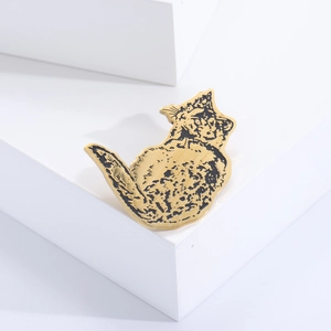 Detailed close-up of a golden cat brooch with fine black etched fur textures on white block