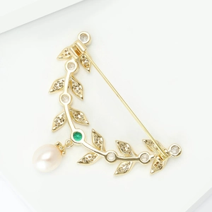 Detail of leaf-shaped gold brooch with micro-pave zircons, green gem and pearl drop