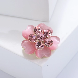 Detail of pink crystal flower brooch with heart petals on a white display stand