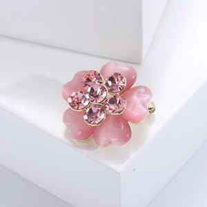 Elegant gold-tone flower brooch with pink cat eye stone petals and crystal center