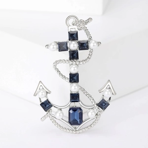Macro shot of silver anchor brooch with blue square gemstone and white round pearls