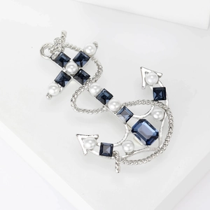 Detailed close-up of retro anchor brooch with navy blue crystals and white pearls