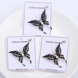 Close-up of black butterfly brooches with white crystals on fashion jewelry cards