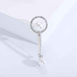 Detailed view of silver key brooch featuring micro-pave crystals and elegant white pearls