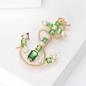 Close-up of vintage anchor brooch with green gemstones and white pearl accents