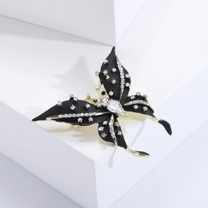 Detail of a black and gold butterfly brooch with rhinestones on a white geometric stand