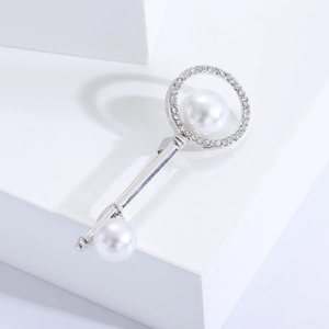 Close-up of silver key brooch with sparkling rhinestones and elegant white pearls