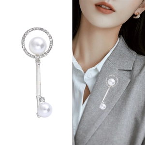 Elegant silver key brooch with white pearls and rhinestones on a grey blazer