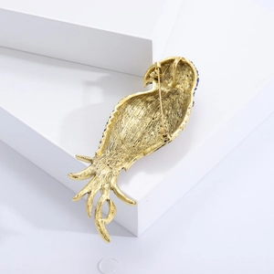 Golden parrot brooch back view with rhinestone details and metal texture on white block