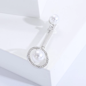 Detailed macro view of silver key brooch with white pearls and sparkling zircon stones