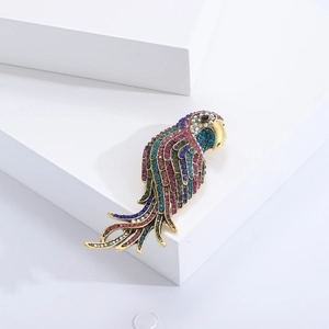 Detailed macro view of gold parrot brooch with colorful rhinestones on white stands