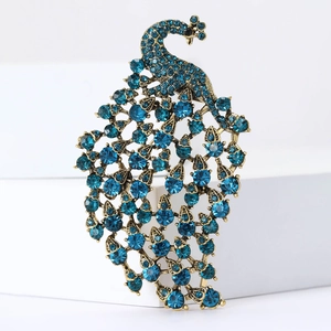 Detail shot of vintage peacock brooch with turquoise rhinestones on antique gold finish