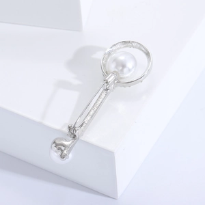 Detailed close-up of a silver key brooch with white pearls and polished alloy finish