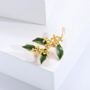 Dettaglio spilla osmanthus dorata con foglie di smalto verde su blocchi bianchi