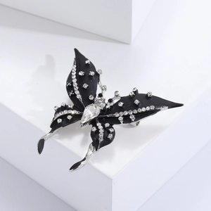 Detailed view of an enamel butterfly brooch with white rhinestones on a white pedestal