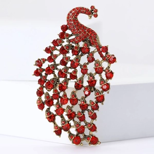 Vintage gold peacock brooch with red rhinestones on a white minimalist background