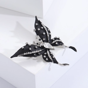 Close-up of matte black butterfly brooch with silver edges and white crystals