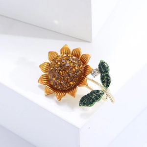 Detail of sunflower brooch with orange petals and brown rhinestones on metal