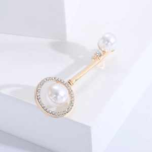 Detailed macro view of gold-plated key brooch featuring white pearls and tiny crystals