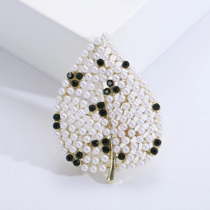 Vue détaillée de la broche feuille dorée ornée de perles blanches et de cristaux verts