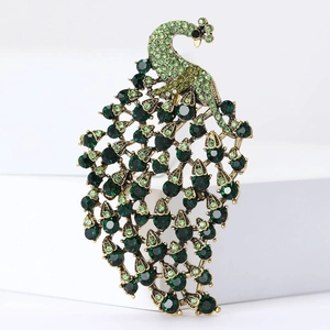 Vintage gold peacock brooch with emerald green crystals on white display stand