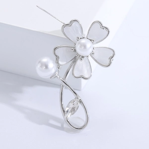 Macro view of shell flower brooch with white enamel petals, pearls and a marquise crystal