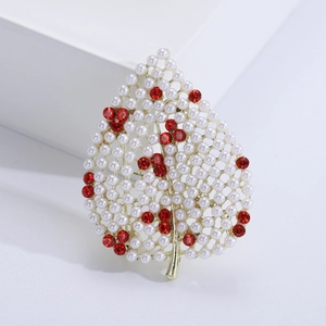 Vue détaillée d'une broche feuille ornée de perles blanches et strass rouges sur alliage doré