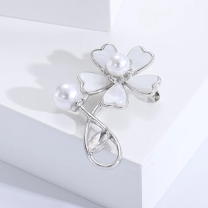 Elegant silver flower brooch with shell petals and central white pearl on white pedestal