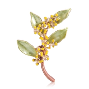 Elegante spilla a fiore di osmanto con foglie verdi e smalto giallo su sfondo bianco pulito