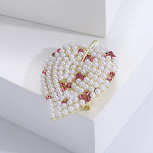 Détail d'une broche feuille avec perles et cristaux roses sur présentoir blanc