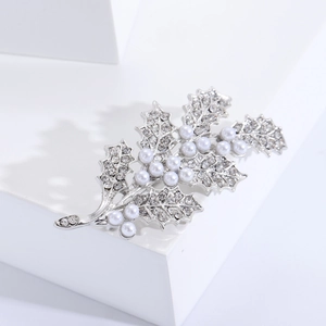 Vue détaillée d'une broche feuille de houx argentée avec cristaux et perles blanches