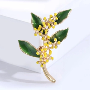 Elegante spilla a fiore di osmanto dorato con foglie in smalto verde su base bianca
