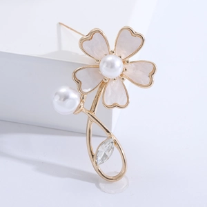 Detail of elegant gold flower brooch with pearl petals and sparkling crystal leaf