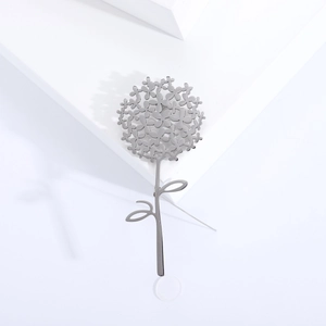 Macro d'une broche pissenlit en argent avec pétales ciselés et tige en métal poli