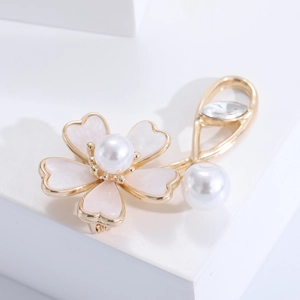 Detailed close-up of shell flower brooch with white enamel petals and pearl center