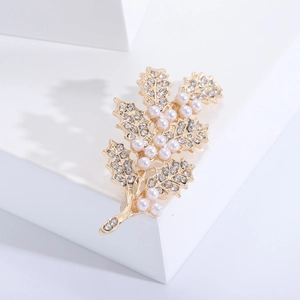 Vue détaillée de la broche feuille dorée avec strass scintillants et perles blanches