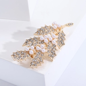 Détail macro d'une élégante broche feuille dorée avec perles blanches et strass brillants