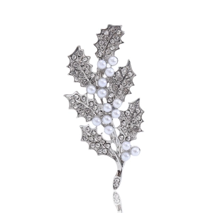 Broche feuille argentée avec perles et strass sur fond blanc avec un reflet élégant
