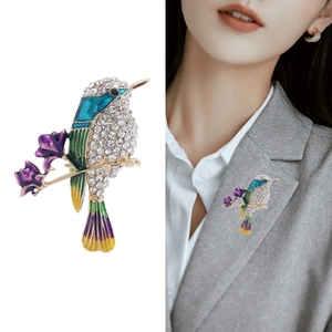 Broche colibri étincelante avec ailes en émail coloré et strass sur blazer gris